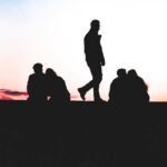 12 apostolos de Jesus: silhuetas de grupo de pessoas ao por do sol representando os discipulos enviados por Cristo